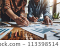 Professional team working together on financial statistics and graphs during a strategic business meeting 113398514
