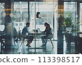 Two colleagues having a conversation with a laptop in a modern office environment 113398517