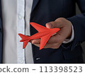 Businessman's hand holding a red paper airplane, representing corporate travel and innovation 113398523