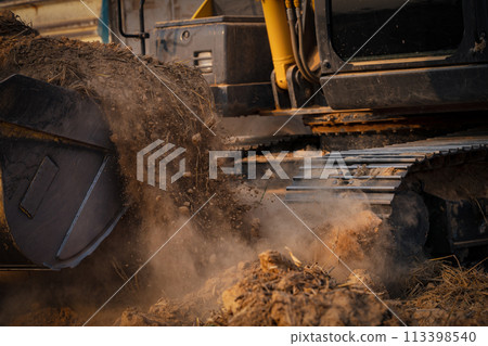 Selective focus on metal bucket teeth of backhoe digging soil. Backhoe working by digging soil at construction site. Crawler excavator digging on soil. Earth moving machine. Excavation vehicle. Selective focus on metal bucket teeth of backhoe digging soil. Backhoe working by digging soil at construction site. Crawler excavator digging on soil. Earth moving machine. Excavation vehicle. 113398540