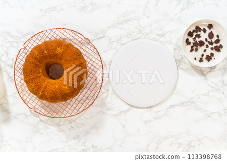 Flat lay. Icing the pumpkin bundt cake with cream cheese frosting and decorating it with chocolate leaves. 113398768