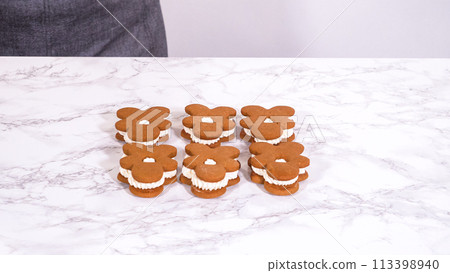 Gingerbread cookies await their second halves on a marble surface, each meticulously piped with buttercream to craft delightful sandwich treats. The precision of the piping adds a festive touch. Gingerbread cookies await their second halves on a marble surface, each meticulously piped with buttercream to craft delightful sandwich treats. The precision of the piping adds a festive touch. 113398940