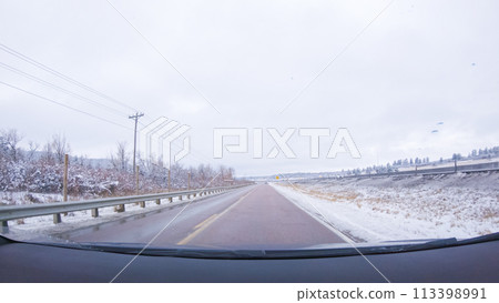 The open highway invites a peaceful drive, with snow-clad pines lining I-25 as the journey continues from Denver towards Colorado Springs on a snowy day. 113398991