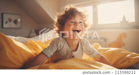 Happy cute laughing child sitting in bed in bedroom. 113399211