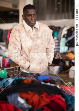 Ordinary Afro-American guy sells hands clothes on flea market Ordinary Afro-American guy sells hands clothes on flea market 113400189