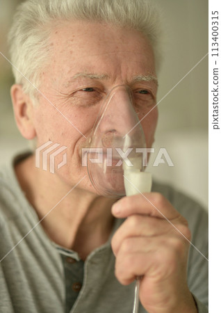 Close-up portrait of an elder man making inhalation 113400315