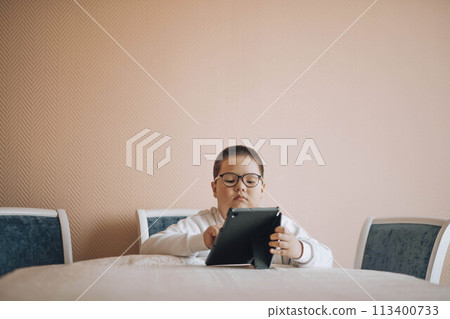 Digital Immersion : A young child is fully engrossed in the digital world through a tablet, symbolizing the blend of modern technology and early education 113400733