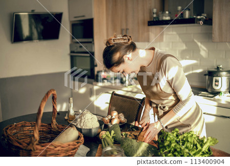 Shoot of athletic woman cutting pumpkin with a knife to prepare in the kitchen at home Shoot of athletic woman cutting pumpkin with a knife to prepare in the kitchen at home 113400904