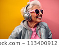 In Tune with Joy: Elderly Elegance in a Pink Hoodie Dances at Home 113400912