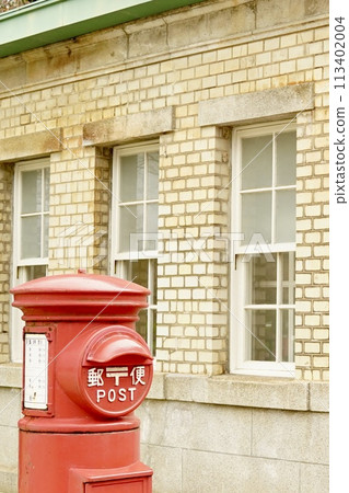 Retro red mailbox and brick building 113402004