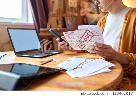 Close up of woman sorting past due bills and debt notices while managing finances, copy space 113402017