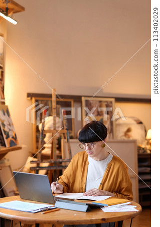 Vertical portrait of adult woman artist using laptop in art studio managing small business copy space Vertical portrait of adult woman artist using laptop in art studio managing small business copy space 113402029