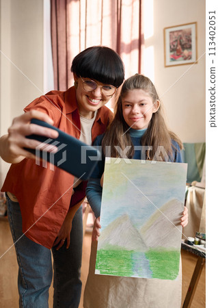 Vertical portrait of female art teacher taking selfie photo with student in studio 113402051
