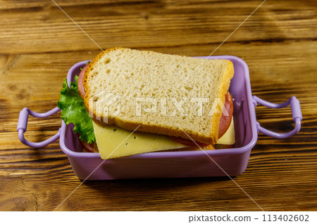 Lunch box with sandwiches on a wooden table 113402602