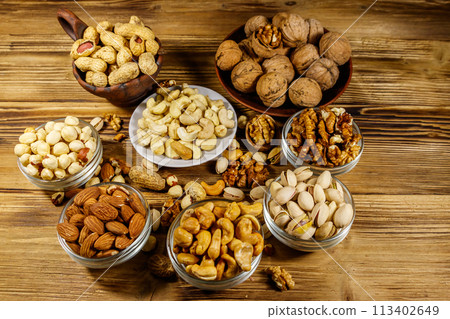 Assortment of nuts on wooden table. Almond, hazelnut, pistachio, peanut, walnut and cashew in small bowls. Healthy eating concept Assortment of nuts on wooden table. Almond, hazelnut, pistachio, peanut, walnut and cashew in small bowls. Healthy eating concept 113402649