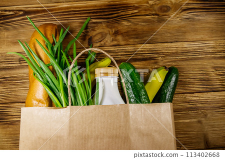 Paper bag with different food on wooden table. Top view. Grocery shopping concept 113402668