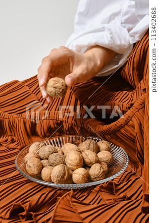 Unrecognizable woman placed a plate of walnuts on the hem of her skirt 113402688
