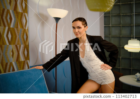 Woman in retro style knitted body suit and oversized jacket posing in living room Woman in retro style knitted body suit and oversized jacket posing in living room 113402713