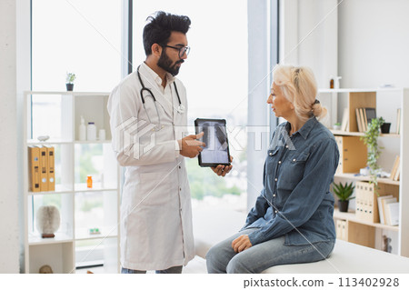 Bearded male in lab coat holding tablet with MRI scan. 113402928