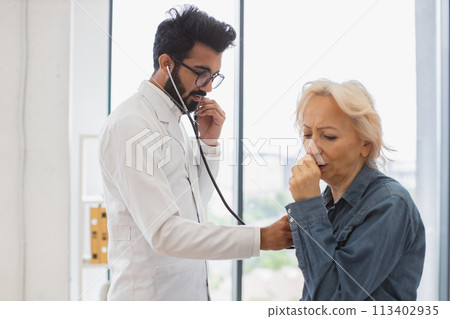 Serious old woman coughing while visiting family doctor for full examination. Serious old woman coughing while visiting family doctor for full examination. 113402935