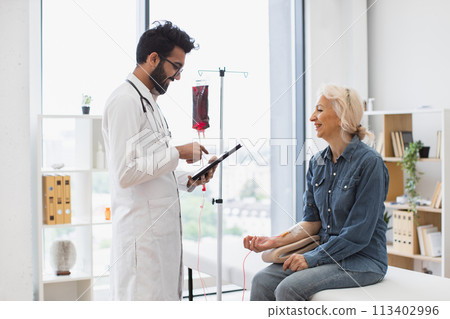 Medical specialist monitoring blood transfusions looking at electronic history. Medical specialist monitoring blood transfusions looking at electronic history. 113402996