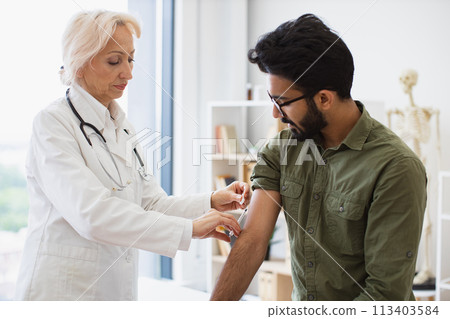 General practitioner giving injection to boost immunity for young patient. 113403584