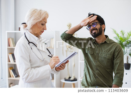 Elder physician giving recommendations and writing prescription. Elder physician giving recommendations and writing prescription. 113403609