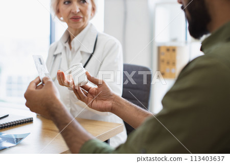 Bearded man keeping bottle and blister of pills and listening to doctor's advice Bearded man keeping bottle and blister of pills and listening to doctor's advice 113403637