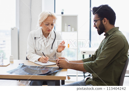 Gentleman describing symptoms of illness to senior female doctor. Gentleman describing symptoms of illness to senior female doctor. 113404242