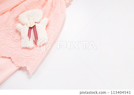 Knitted bear and romper on white background. Copy space. Baby born concept. Flat lay Knitted bear and romper on white background. Copy space. Baby born concept. Flat lay 113404541