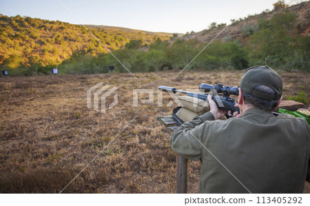 Man shoots rifle with optics at shooting range before hunting. 113405292