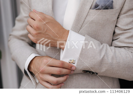 Close-up of a man fastening a cufflink on his shirt 113406129