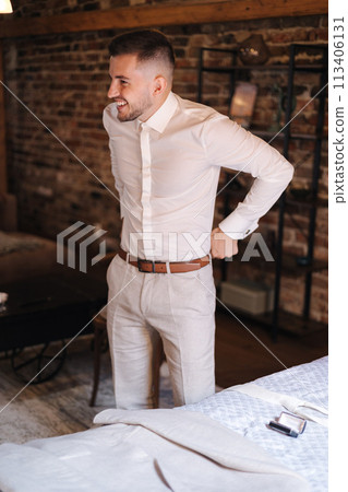 Young and stylish man wears light suit. Handsome man smile. Background of brick wall 113406131