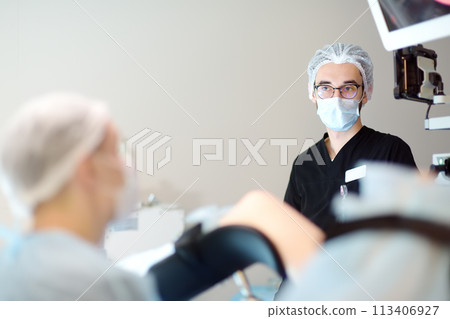 Gynecologist and assistant operating patient in gynecological chair. Doctor performs invasive medical procedure in modern hospital. Diagnosis of cervical cancer. Surgical removal of uterine cyst Gynecologist and assistant operating patient in gynecological chair. Doctor performs invasive medical procedure in modern hospital. Diagnosis of cervical cancer. Surgical removal of uterine cyst 113406927