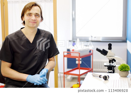 Portrait of male dermatologist in office in modern clinic. Doctor during appointment of patient at work place. Portrait of male dermatologist in office in modern clinic. Doctor during appointment of patient at work place. 113406928