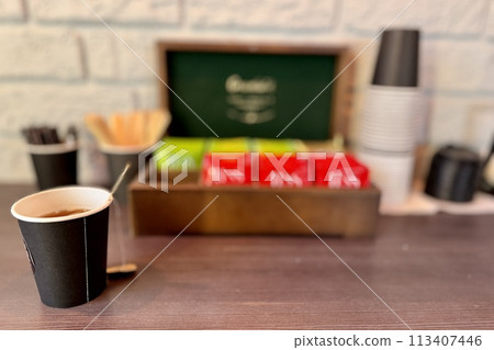 Box with different types of black and green tea and carton cup is located on a wooden table. Free tea drinking area in the car dealership for customers Box with different types of black and green tea and carton cup is located on a wooden table. Free tea drinking area in the car dealership for customers 113407446