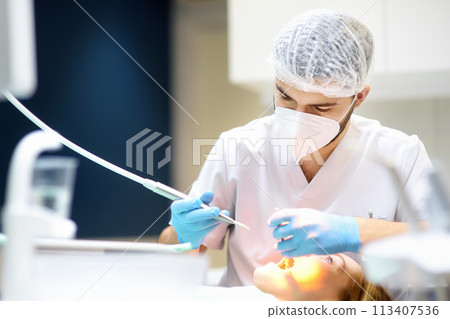 Dentist and patient at modern medical center. Doctor treats a young woman teeth in hospital. Practitioner examines the patient before orthodontists or prosthetics treatment. Dentist and patient at modern medical center. Doctor treats a young woman teeth in hospital. Practitioner examines the patient before orthodontists or prosthetics treatment. 113407536