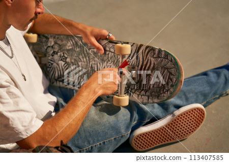 Close up of a man repairing his skateboard in the skate park. Extreme sport concept 113407585