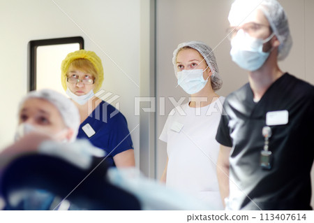 A surgeon, an assistant, an intern and a nurse observe the progress of a surgical operation on a portable screen in the operating room of a modern medical hospital. A surgeon, an assistant, an intern and a nurse observe the progress of a surgical operation on a portable screen in the operating room of a modern medical hospital. 113407614
