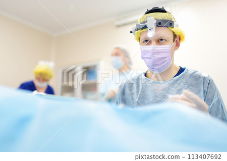 Surgeons are during maxillofacial operation using microscope and endoscope in modern hospital. Teamwork of doctors. Maxillofacial surgery. 113407692