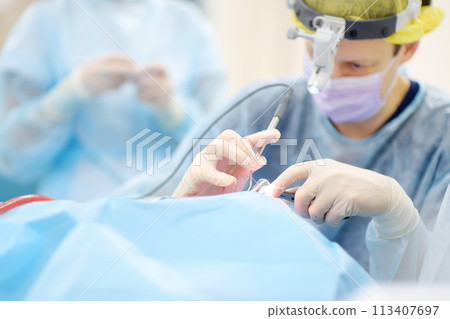 Surgeons are during maxillofacial operation using microscope and endoscope in modern hospital. Teamwork of doctors. Maxillofacial surgery. 113407697