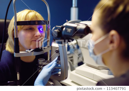 Slit Lamp eye examination with ophthalmologist. Patient during visit by oculist for exam of biomicroscopic analysis of eyelids, sclera, conjunctiva, iris, lens, cornea. Checkup of retina and fundus 113407791
