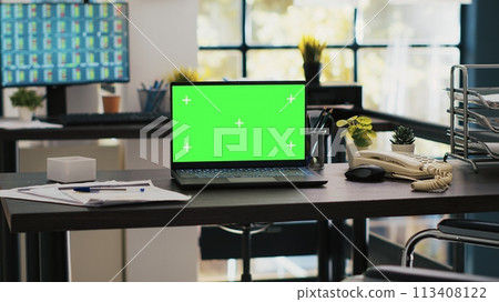 Wheelchair in office offering accessibility to workers with disability and green screen laptop on desk. Mockup notebook in workspace and computer screen in background displaying stock exchange 113408122