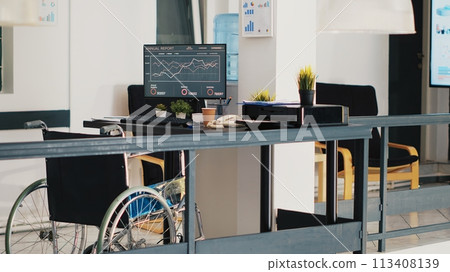 Wheelchair in inclusive accounting department office with forecasting profit analysis on laptop. Economic annual revenue trends on notebook in workspace with accessibility for workers, panning shot Wheelchair in inclusive accounting department office with forecasting profit analysis on laptop. Economic annual revenue trends on notebook in workspace with accessibility for workers, panning shot 113408139