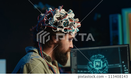 IT specialist using EEG headset and deep learning technology to upload brain into computer. Close up of neuroscientific equipment used by man transferring consciousness into cyberspace, camera A IT specialist using EEG headset and deep learning technology to upload brain into computer. Close up of neuroscientific equipment used by man transferring consciousness into cyberspace, camera A 113408143