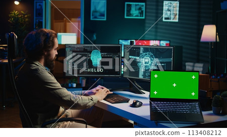 Engineer with EEG headset on programming brain transfer into computer virtual world next to green screen laptop. Transhumanist using neuroscience to gain digital soul, mockup device, camera A Engineer with EEG headset on programming brain transfer into computer virtual world next to green screen laptop. Transhumanist using neuroscience to gain digital soul, mockup device, camera A 113408212