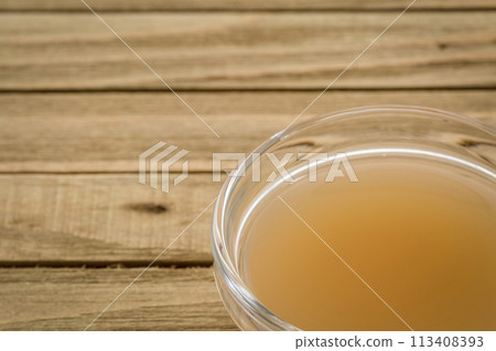 unfiltered, raw apple cider vinegar with mother - a small glass bowl on wooden table 113408393