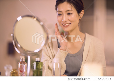 Middle-aged woman doing night skin care Middle-aged woman doing night skin care 113409423