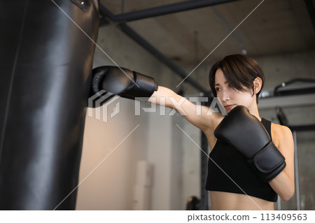 A cool, handsome woman boxing or boxercise in the gym A cool, handsome woman boxing or boxercise in the gym 113409563