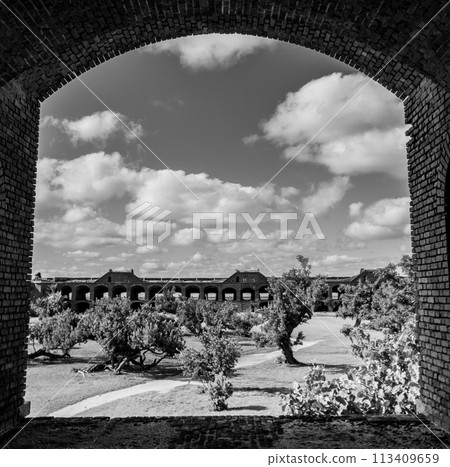 View through an open archway in Fort Jefferson on Dry Tortugas National Park with a the open courtyard a parade ground in the distance. 113409659